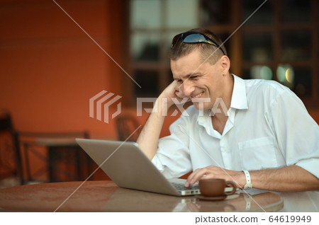 Man using laptop with cup of coffee Man using laptop with cup of coffee 64619949