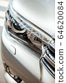 Closeup of a car headlight. Headlight of an expensive new car at a car dealership. 64620084