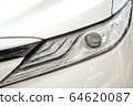 Closeup of a car headlight. Headlight of an expensive new car at a car dealership. 64620087