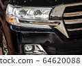 Closeup of a car headlight. Headlight of an expensive new car at a car dealership. 64620088