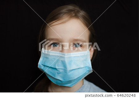 Coronavirus Covid-19 outbreak. Little blonde girl wearing light blue disposable mask for protection of virus on black background in studio. Quarantine concept Coronavirus Covid-19 outbreak. Little blonde girl wearing light blue disposable mask for protection of virus on black background in studio. Quarantine concept 64620248