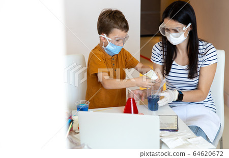 Attentive little boy adding powder into blue water Attentive little boy adding powder into blue water 64620672