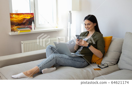 Beautiful young woman using smartphone at home Beautiful young woman using smartphone at home 64621174