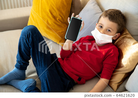Bored kid using smartphone on sofa during quarantine Bored kid using smartphone on sofa during quarantine 64621620