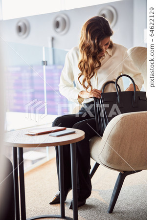 Beautiful young woman searching something in her bag 64622129