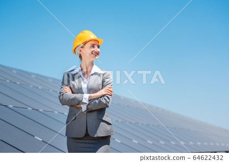 Woman investor in clean energy standing in front of solar panels 64622432
