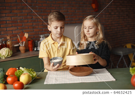 Children playing with a flour in a kitchen Children playing with a flour in a kitchen 64632425