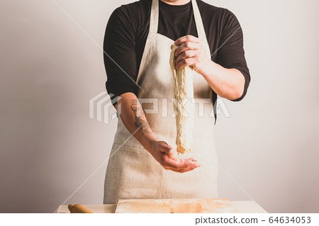 Concept process of making alternative yeast-free home-made bread. A man kneads a kneading pot with dough on the table. Concept process of making alternative yeast-free home-made bread. A man kneads a kneading pot with dough on the table. 64634053