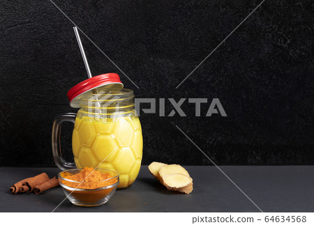 Mason jar of golden turmeric milk with metal straw, ingredients for its cooking on black background. Turmeric milk is organic indian ayurvedic healthy drink for improve immunity. Copy space. 64634568