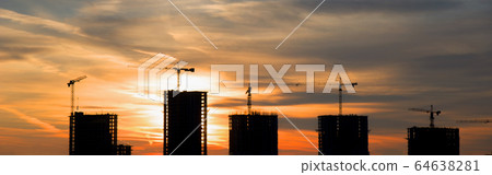 Silhouettes of tower cranes constructing a new residential building at construction site on sunset  64638281