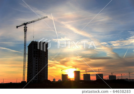 Silhouettes of tower cranes constructing a new residential building at construction site on sunset  64638283