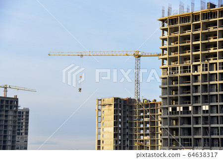 Tower cranes working at construction site against blue sky 64638317