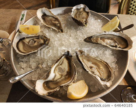 Fresh Oysters with lime on a large plate with ice. Fresh Oysters with lime on a large plate with ice. 64640185