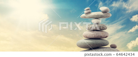 Pyramid of sea pebbles over a sunny sky Pyramid of sea pebbles over a sunny sky 64642434