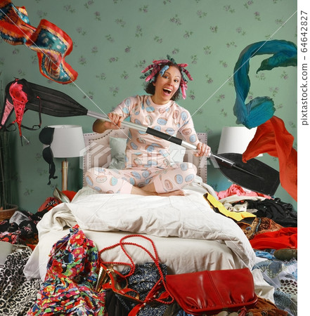 Woman sitting on a bed paddles as if in a boat Woman sitting on a bed paddles as if in a boat 64642827