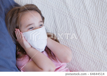 Portrait of a child who covered her face with a mask. A girl is home-schooled. The concept of quarantine, self-isolation, protection from coronavirus, virus, fear of disease, treatment, medicine Portrait of a child who covered her face with a mask. A girl is home-schooled. The concept of quarantine, self-isolation, protection from coronavirus, virus, fear of disease, treatment, medicine 64644514
