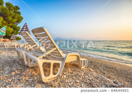 Sun loungers and beach umbrellas at sunset on the 64644891