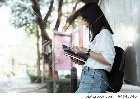 Girl reading a books at bus station Girl reading a books at bus station 64646340
