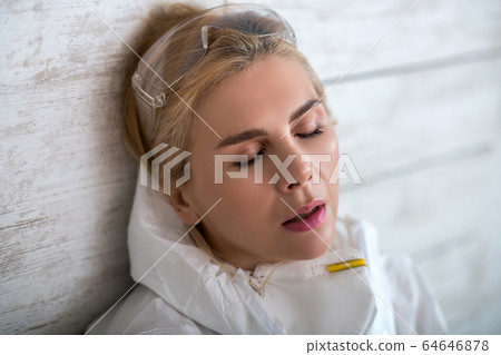 Blonde woman in white workwear sufferning from headache 64646878