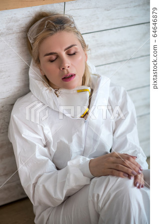 Blonde woman in white workwear looking exhausted Blonde woman in white workwear looking exhausted 64646879