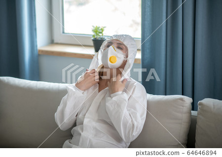 Woman in white workwear and respirator feeling tired 64646894