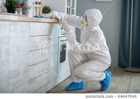 Woman in white workwear and protective gloves cleaning the surface 64647048