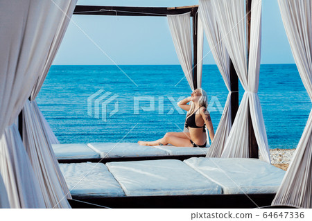woman in bathing suit sunning on the beach 64647336