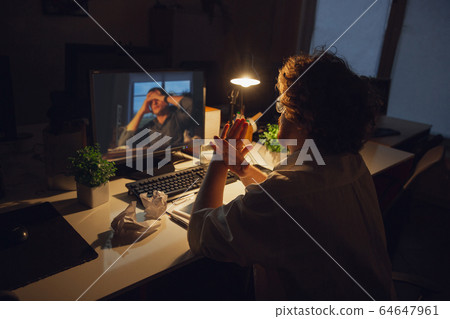 Man working in office alone during coronavirus or COVID-19 quarantine, staying to late night 64647961
