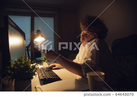 Man working in office alone during coronavirus or COVID-19 quarantine, staying to late night 64648070