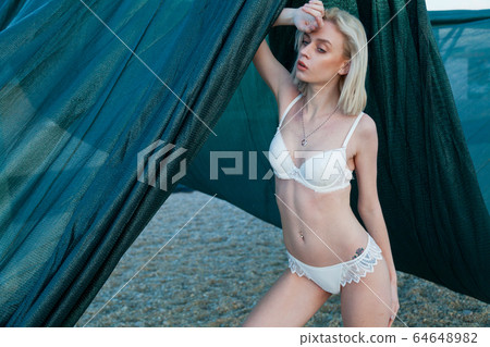 Portrait of a beautiful fashionable blonde woman on an empty beach by the sea 64648982