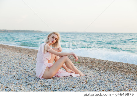 Portrait of a beautiful fashionable blonde woman on an empty beach by the sea Portrait of a beautiful fashionable blonde woman on an empty beach by the sea 64649979