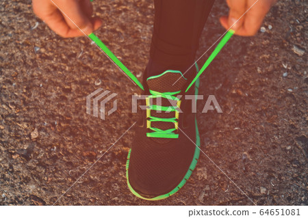 Close up of a sporty woman tying shoelaces on 64651081