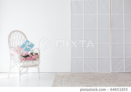 white vintage chair with gift and flowers in the interior of the white room 64651855
