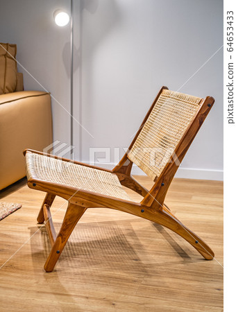 Modern wicker chair standing in a living room with gray wall and floor lamp. Interior wooden furniture Modern wicker chair standing in a living room with gray wall and floor lamp. Interior wooden furniture 64653433