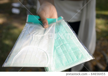 Hand of woman with face mask for Covid-19 protection,generous girl sharing medical mask and raised her hand up,giving hygienic mask to prevent Coronavirus pandemic,spreading contagious disease,flu 64656455