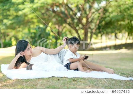 Young Asian mother relax by lie on white carpet near her little baby and her son Young Asian mother relax by lie on white carpet near her little baby and her son 64657425