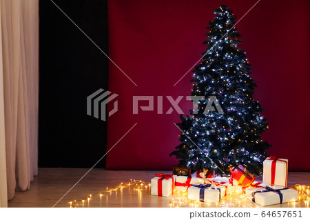 Christmas tree garland lights with new year's gifts red background 64657651