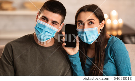 Couple wearing surgical mask using smart phone 64658018