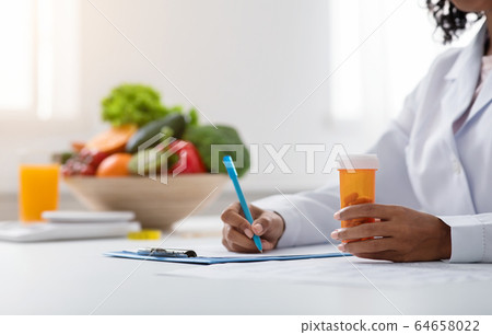 Cropped of black woman doctor dietologist prescribing pills Cropped of black woman doctor dietologist prescribing pills 64658022