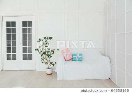 white sofa with gifts in the interior of the white room 64658156