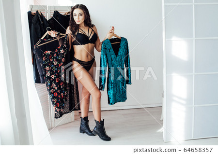 Beautiful brunette woman tries dressing room wardrobe 64658357