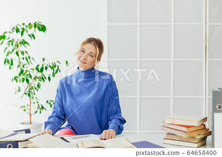 business woman working at a desk in the office with books training 64658400