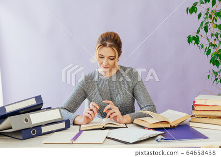 business woman working at a desk in the office with books training business woman working at a desk in the office with books training 64658438