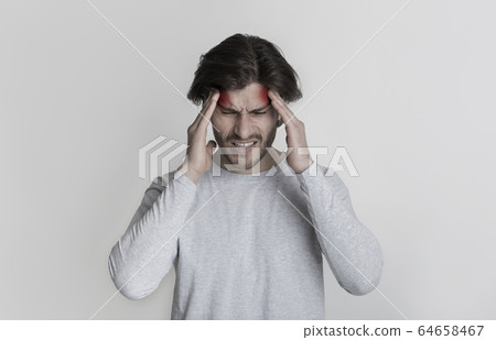 Man holds on to head, highlighted by red spots 64658467