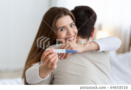 Focus on pregnancy test. Young husband and wife hugging Focus on pregnancy test. Young husband and wife hugging 64658516
