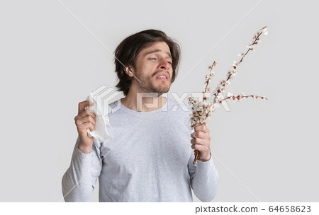 Allergy and bad feeling concept. Man holds flowers 64658623