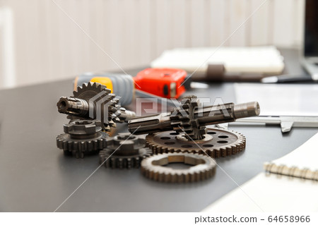 Gear with machine part on engineer desk. 64658966