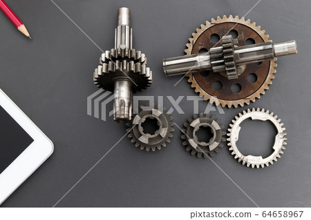 Top view of gear with machine part on engineer desk. Top view of gear with machine part on engineer desk. 64658967