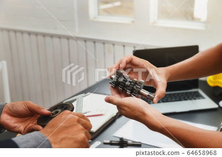 Engineers try to assemble machine parts together. 64658968