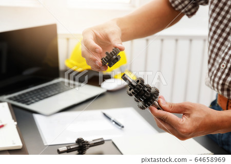 Engineers try to assemble machine parts together. 64658969